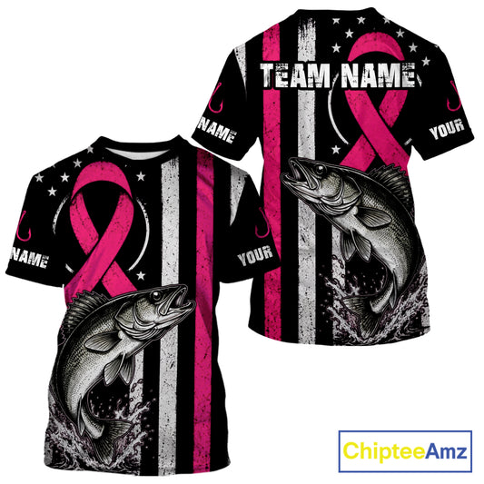 Two views of a customizable short-sleeve t-shirt with a black and white distressed American flag design, a large pink awareness ribbon, a fish graphic, and placeholder text 'TEAM NAME' and 'NAME'.