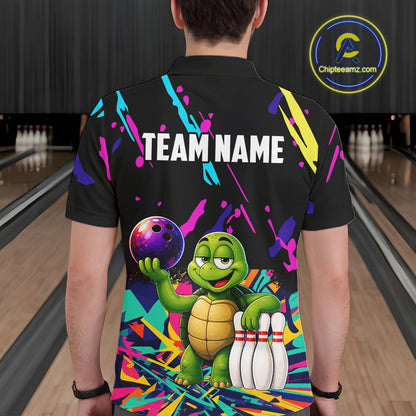 Person wearing a black bowling shirt with colorful design and turtle graphic in a bowling alley.