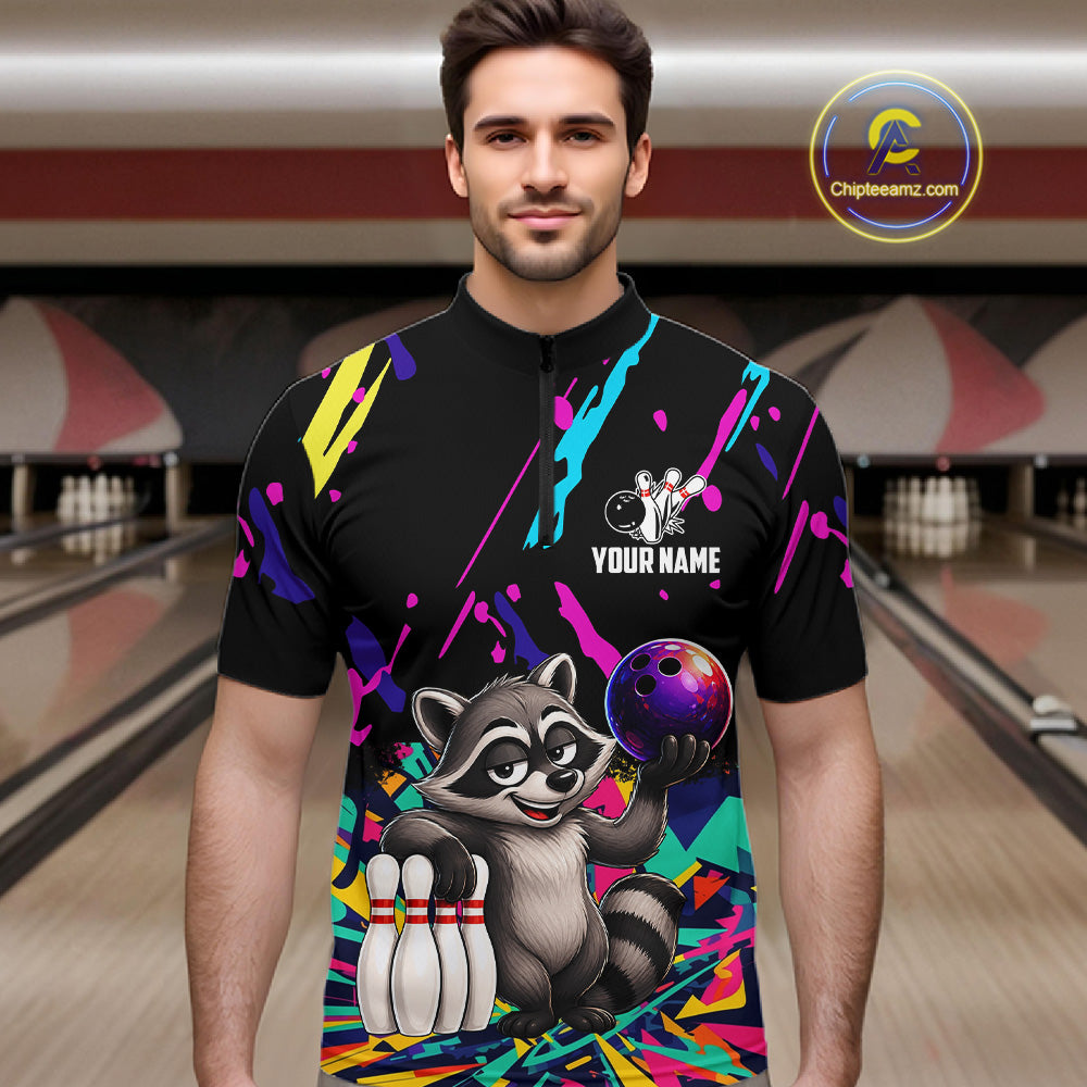 Person wearing a colorful bowling-themed shirt with a raccoon design in a bowling alley.